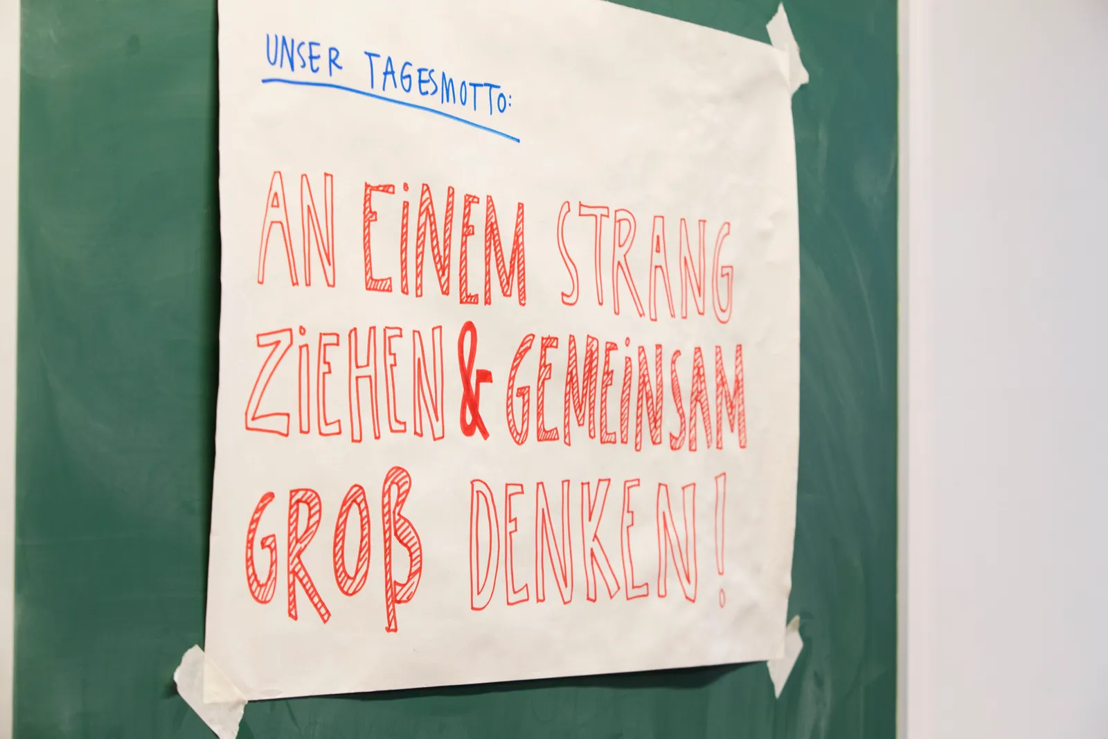 Ein Plakat im Klassenraum trägt das Motto „An einem Strang ziehen & gemeinsam groß denken“.